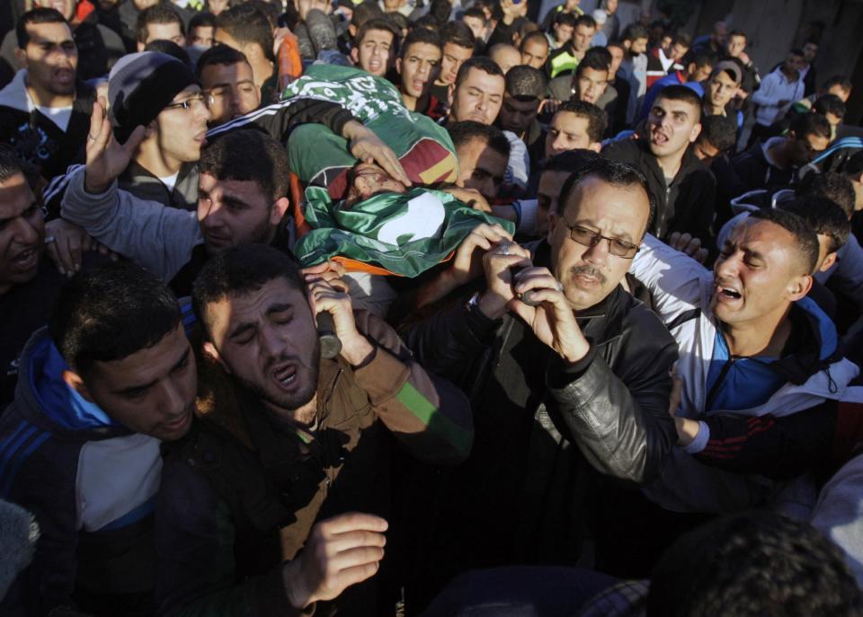 Palestinians carry the body of Hamza Abu el-Heija, who was killed in a raid by Israeli troops, during his funeral procession, in the West Bank refugee camp of Jenin, Saturday, March 22, 2014. Israeli troops killed at least four Palestinians in an early morning raid that was followed by a clash with angry protesters in a West Bank town on Saturday, the Israeli military and Palestinian security officials said, in the deadliest incident in months. The Israeli military said the raid aimed to arrest Hamza Abu el-Heija, a 22-year-old Hamas operative wanted for involvement in shooting and bombing attacks against Israelis. (AP Photo/Mohammed Ballas)