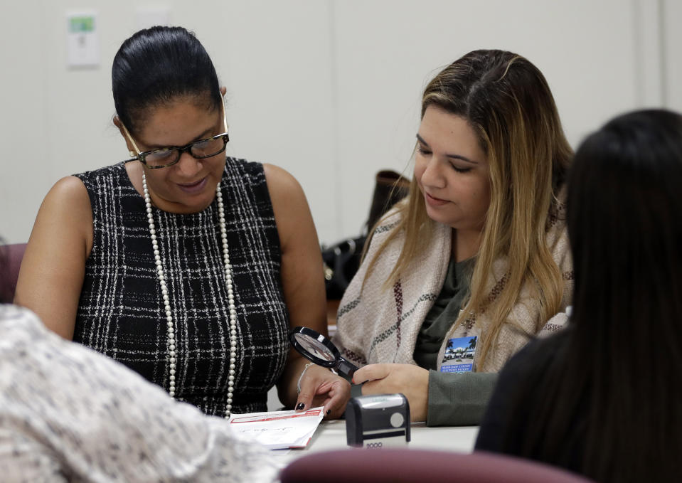 Canvassing board members Judge Tanya Brinkley, left, and Judge Victoria Ferrer, right, verify signatures on mail in ballots at the Miami-Dade County Elections Department, Tuesday, Oct. 30, 2018, in Miami. Voters go to the polls for midterm elections Nov. 6. (AP Photo/Lynne Sladky)