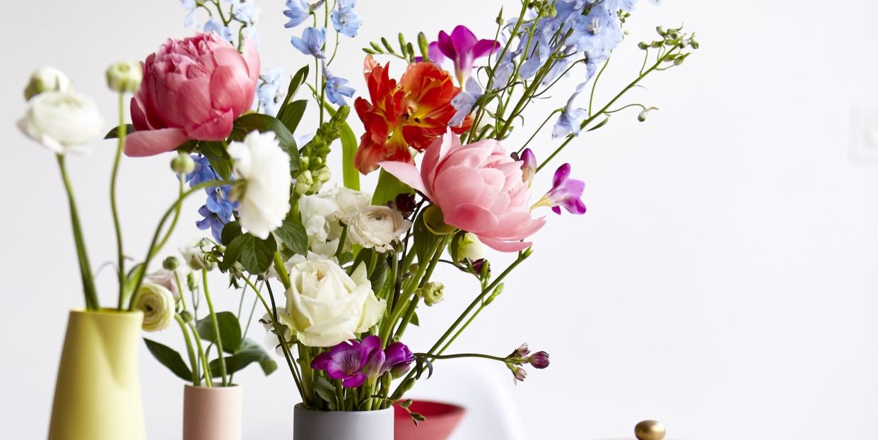 dinning room tabel with a colurful table cloth bowls cups and vases full of flowers on the table