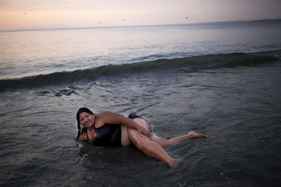 In this Jan. 17, 2013 photo, Yuseth Vazquez wades in the shallow waters of Agua Dulce beach in Lima, Peru. While Lima's elite spends its summer weekends in gate beach enclaves south of the Peruvian capital, the working class jams by the thousands on a single municipal beach of grayish-brown sands and gentle waves. On some weekends during the Southern Hemisphere summer, which runs from December until March, as many as 40,000 people a day visit the half-mile-long (kilometer-long) strip of Agua Dulce. (AP Photo/Rodrigo Abd)