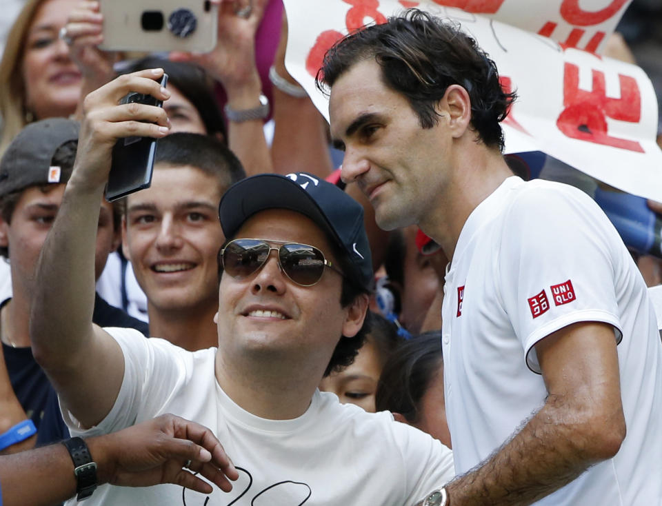 Roger Federer, of Switzerland, poses with a fan after defeating Nick Kyrgios, of Australia, during the third round of the U.S. Open tennis tournament, Saturday, Sept. 1, 2018, in New York. (AP Photo/Jason DeCrow)