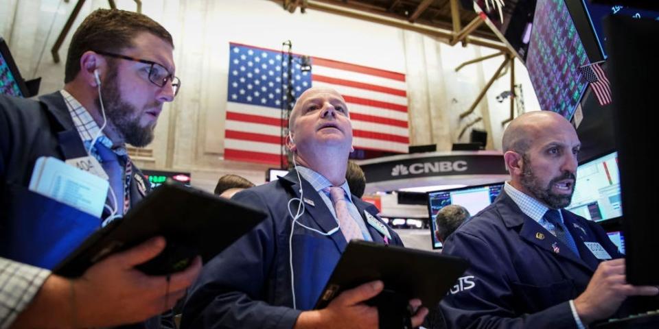 An American flag hangs behind traders working on the floor of the New York Stock Exchange (NYSE) on October 11, 2019 in New York City.