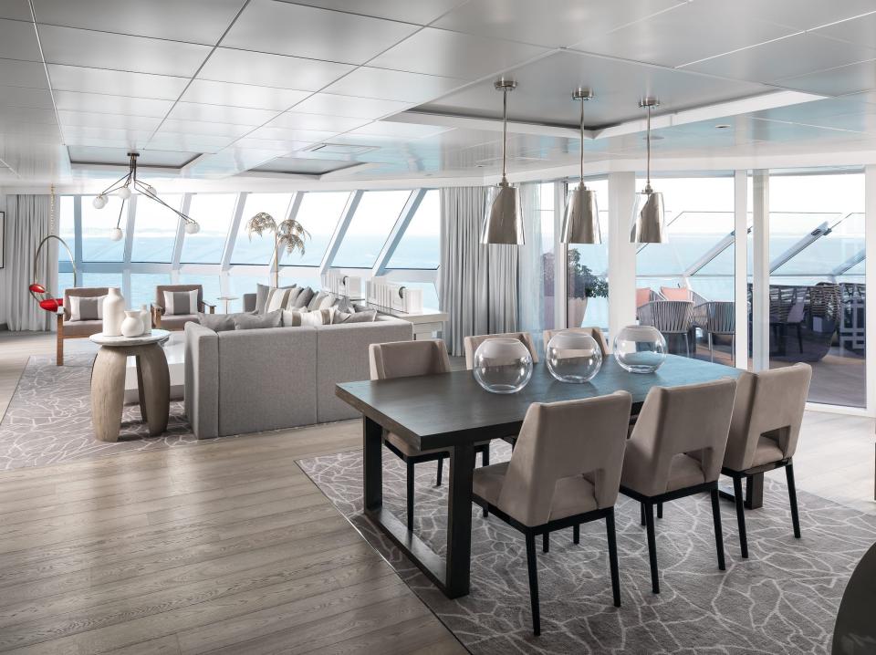 a dining table next to couches and panoramic windows in the Iconic suite aboard the Celebrity Apex cruise ship