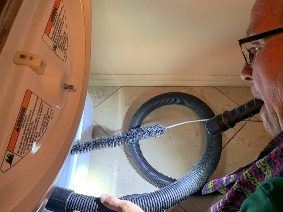 Ryan Arledge unscrews the front of a dryer before cleaning it July 7, 2023.