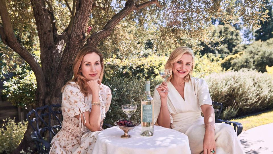 Cameron Diaz and Katherine Power sitting outdoors and showcasing their Avaline wine