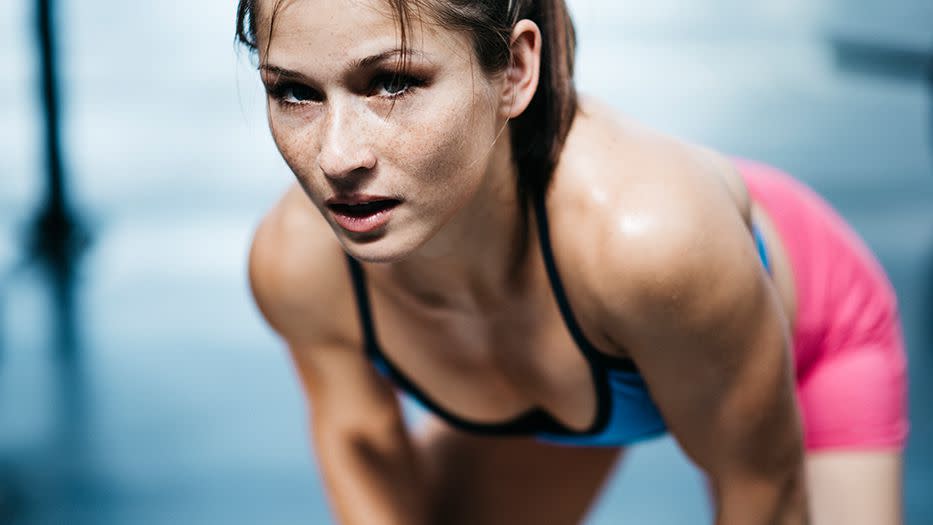 woman leaning over and looking at the camera, presumably after doing a high-intensity workout