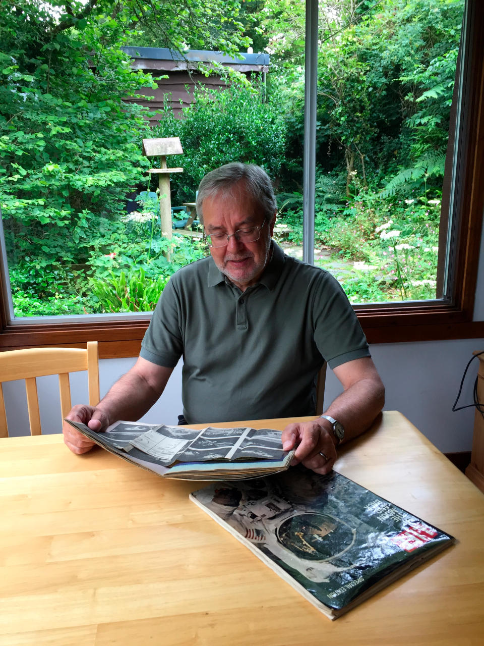 This June 25, 2019 photo provided by Peter Cowin shows him looking over Apollo 11 memorabilia at his home in Cheltenham, England. On July 21, 1969, Peter rolled out of bed around 3 a.m. to watch the moon landing. “I was something of a space junkie at the time,” he said. He was 13 and the only one in his family to wake up because the others were resting up for their vacation that started later that day. “At first the picture was upside down and horribly grainy, but it improved as time went on so I could see two ghostly figures - raising the flag, setting up experiments, and taking that 'giant leap for mankind'. The day after, it seemed as if the whole world was celebrating and uplifted at the thought of what 'we' had achieved. The moon landings showed us that mankind could achieve absolutely anything it set its mind to." (Courtesy Peter Cowin via AP)