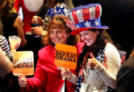 People hold up signs saying, "Defend Freedom, Defeat Obama", while wearing patriotic hats during Mitt Romney's campaign election night event at the Boston Convention & Exhibition Center on November 6, 2012 in Boston, Massachusetts. (Photo by Joe Raedle/Getty Images)