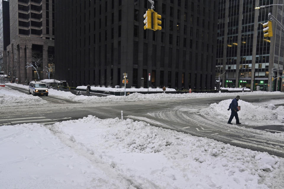 People and cars make their way through a snowy and mostly empty midtown Manhattan in New York, Tuesday, Feb. 2, 2021. Tuesday's snowfall comes as residents of the New York City region are digging out from under piles of snow that shut down public transport, canceled flights and closed coronavirus vaccination sites. (AP Photo/Seth Wenig)