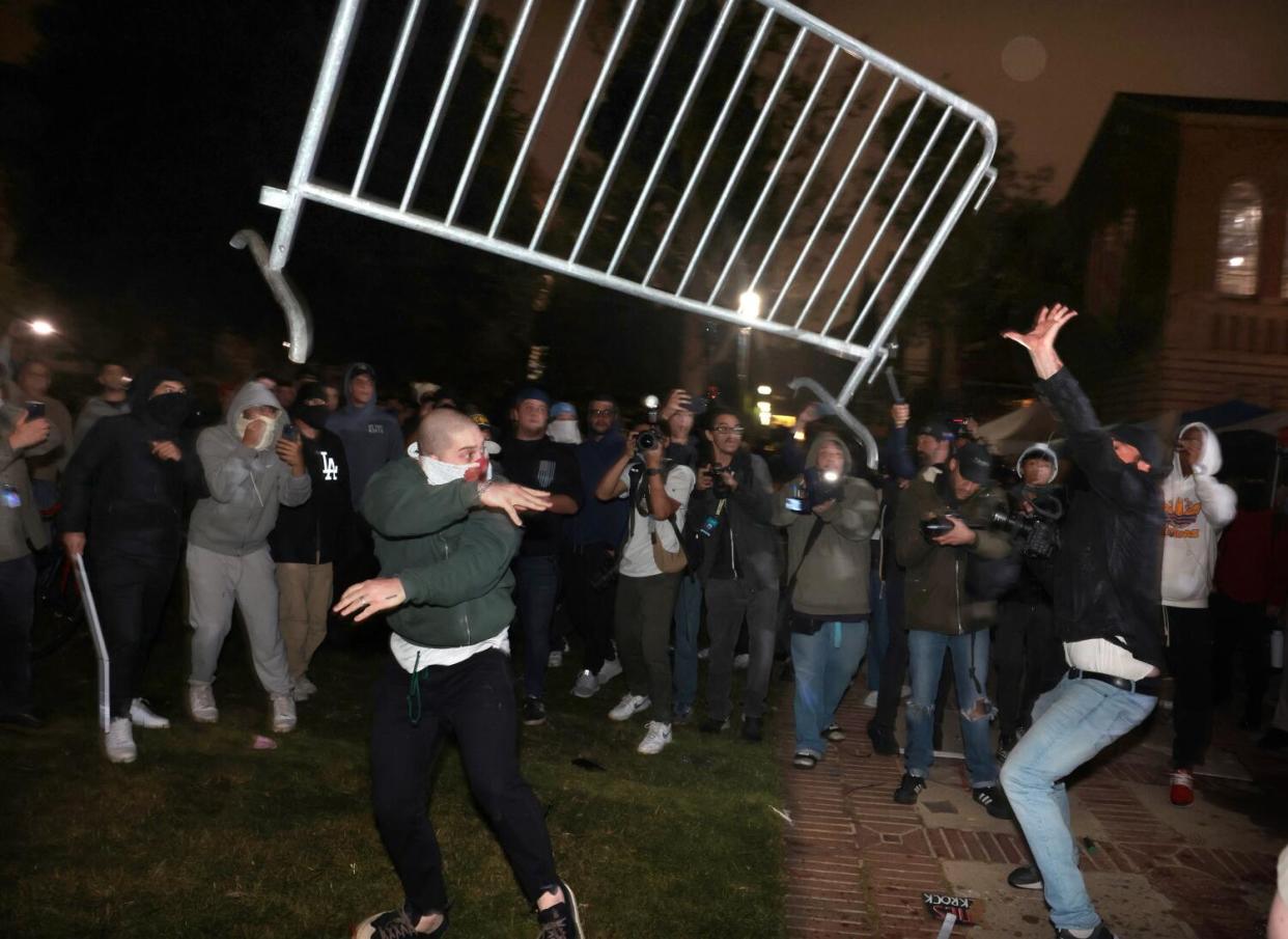 Pro-Palestinian protesters and pro-Israeli supporters clash while a metal barricade goes airborne.