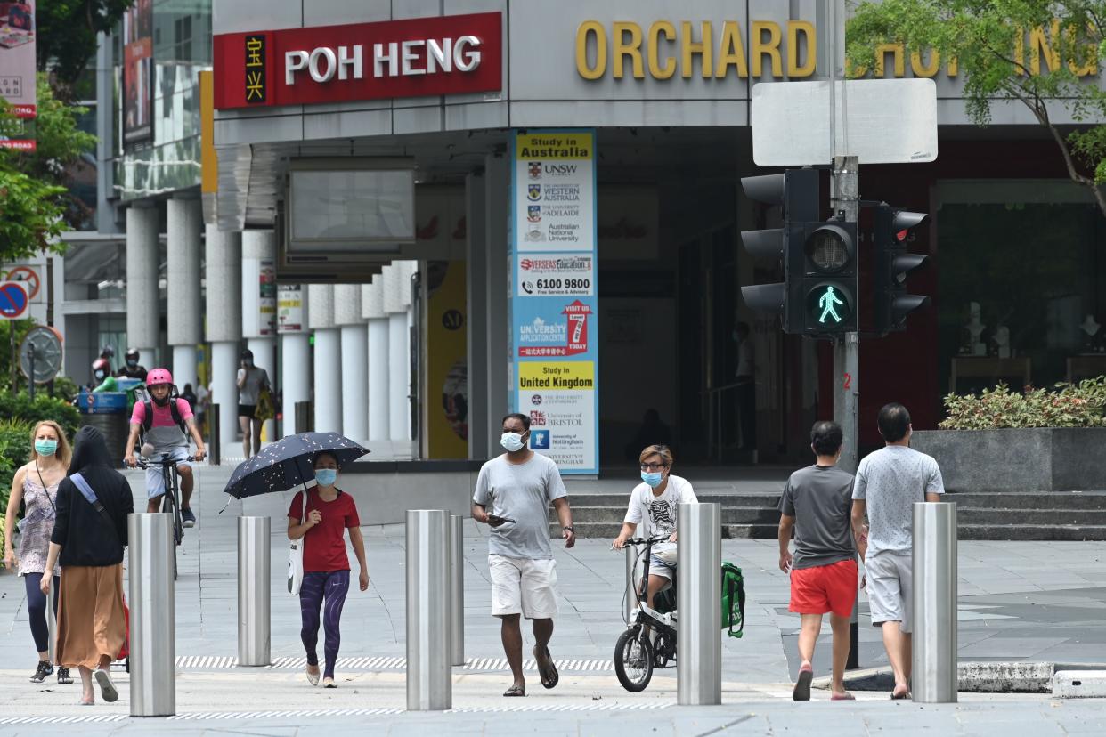 People, wearing face masks as a preventive measure, cross a road along the Orchard Road shopping belt here on 6 May, 2020. (PHOTO: AFP via Getty Images)