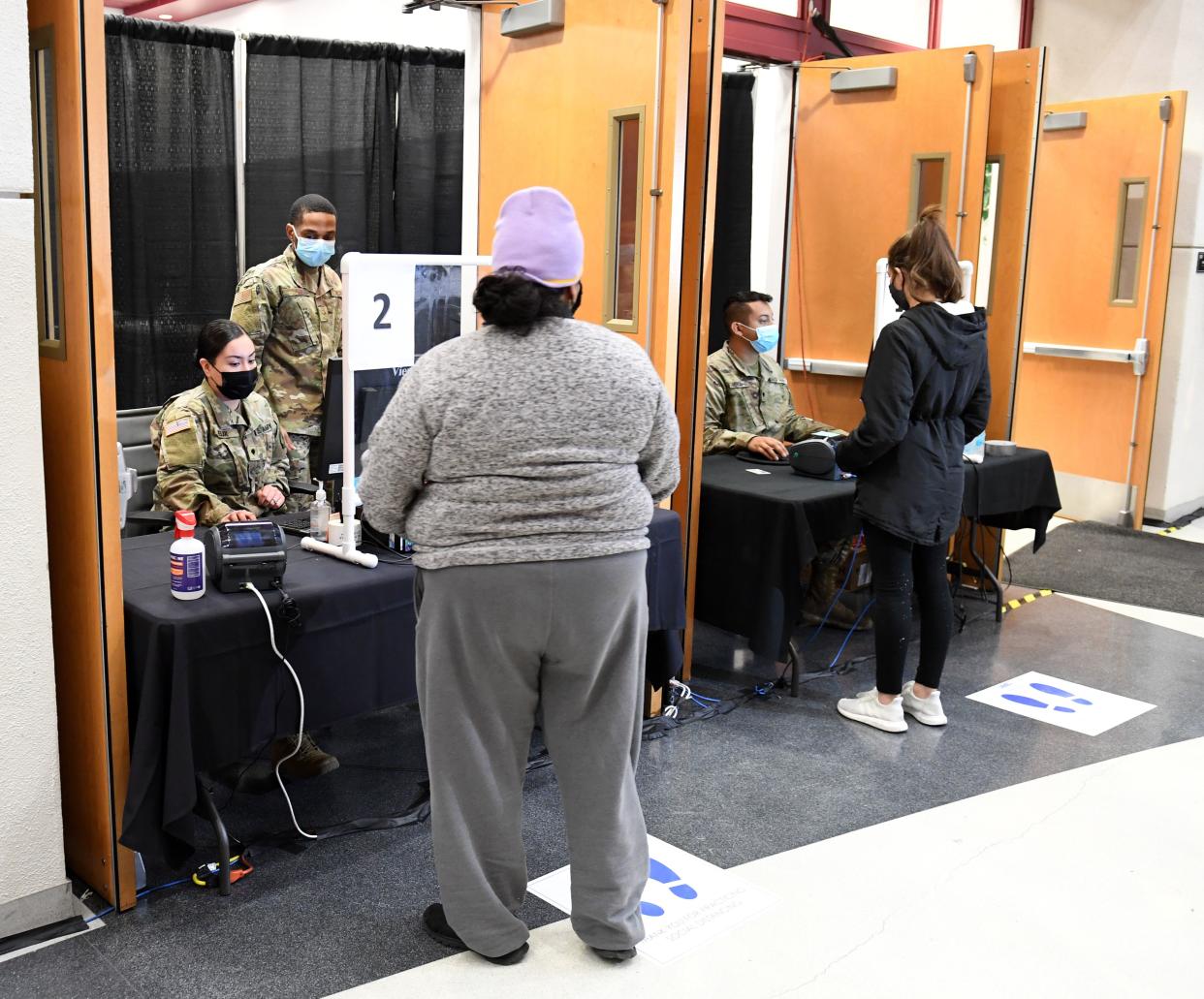 (L-R) Spc. Alondra Felix and Airman 1st Class Kevin Davis of the Nevada National Guard registers Ana Pena for a coronavirus (COVID-19) test as Spc. Daniel Merchant of the Nevada National Guard registers Karina Lewis for a test during a preview of a testing site at the Stan Fulton - International Gaming Institute Building at UNLV on Nov. 30, 2020, in Las Vegas, Nevada. The state set its two highest single-day COVID-19 case records and surpassed 150,000 total cases last week. Nevada has seen a sharp upward climb in the test positivity rate since the end of October, which has now grown to more than 17 percent. Clark County and University Medical Center of Southern Nevada are operating the new site, which has separate areas for people who arrive with and without symptoms of COVID-19, in partnership with the Nevada National Guard and University Police Services.