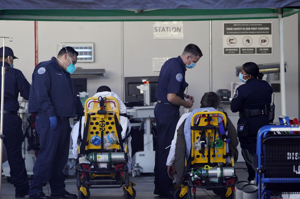 Los Angeles County emergency medical technicians deliver patients for admission at the Ambulatory Care Center station at the MLK Community Medical Group hospital in Los Angeles, Wednesday, Feb. 24, 2021. (AP Photo/Damian Dovarganes)