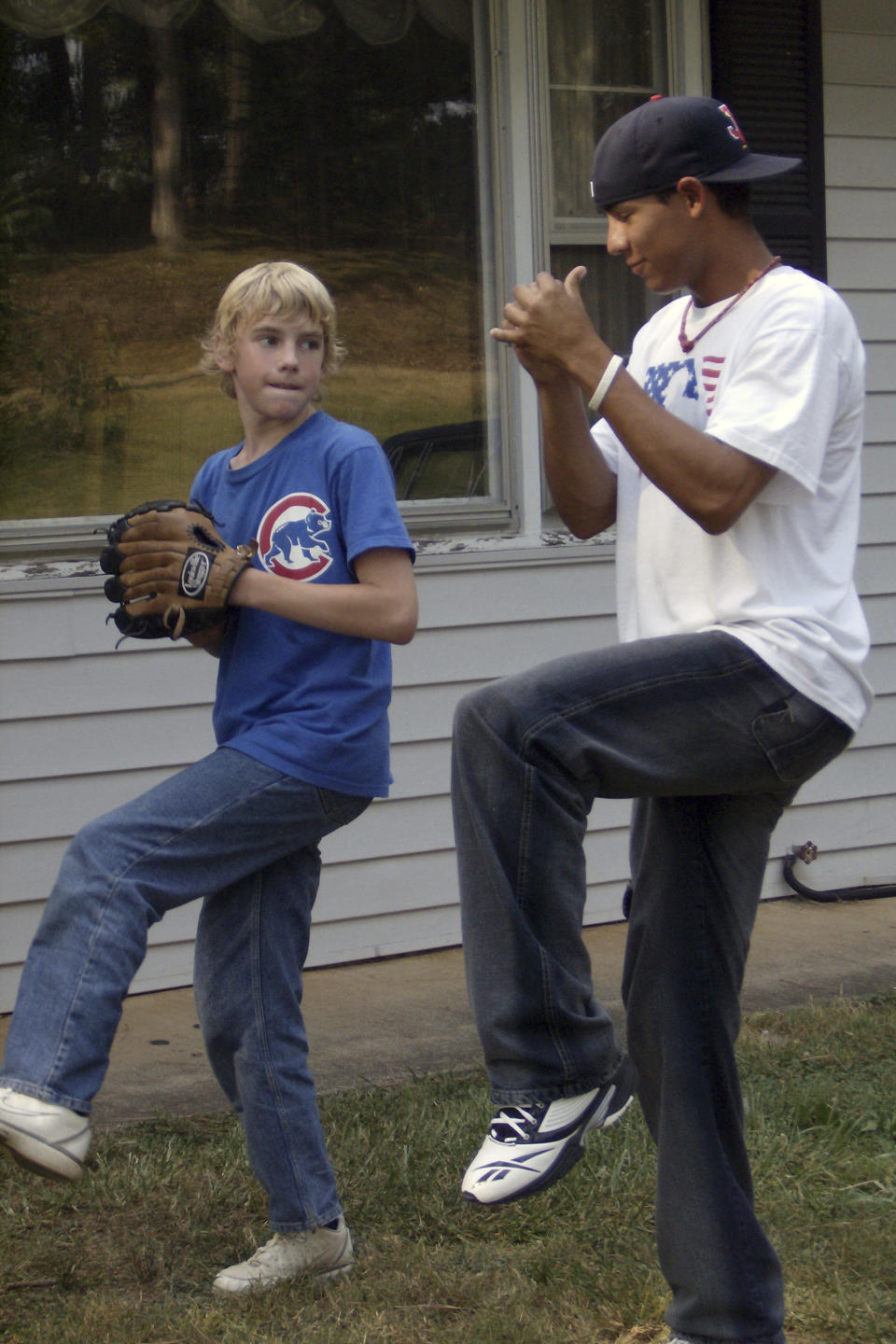 In this photo provided by TeriAnn Reynolds, Mathew Reynolds, left, and minor league baseball player Eduardo Sanchez, of Venezuela, play outside the host family residence in Johnson City, Tenn., in August 2007. The role of host families varied from place to place, but for most, it was pretty basic. Players usually got a room, a bed and access to a few good meals each day. (Photo courtesy TeriAnn Reynolds via AP)