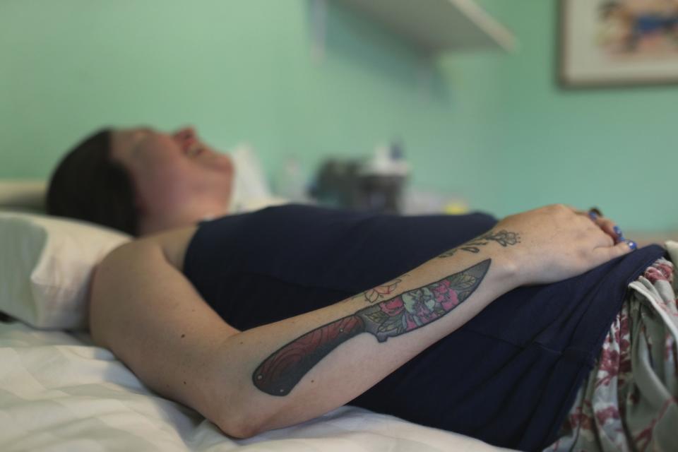 FILE - Ana Estrada, a Peruvian psychologist who is almost completely paralyzed by a terminal illness, rests in her bedroom in Lima, Peru, Dec. 18, 2019. Estrada, who suffered from an incurable disease and was authorized in 2022 by Peru's Supreme Court to receive euthanasia, has died, her lawyer said Monday, April 22, 2024. She has seven tattoos - birds, plants, a dagger - that she says remind her that "life is beautiful." She said the knife represents a weapon that defends her freedom to write. She is the author of a blog titled; "For a dignified death." (AP Photo/Martin Mejia, File)