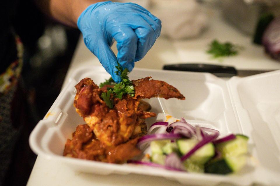 Josmine Evans of Indigo Culinary prepares a dish with chicken wings tossed in maafe sauce and served with fried rice balls, cucumber spears and red onion at Two Birds in Detroit's west village neighborhood on January 27, 2023.