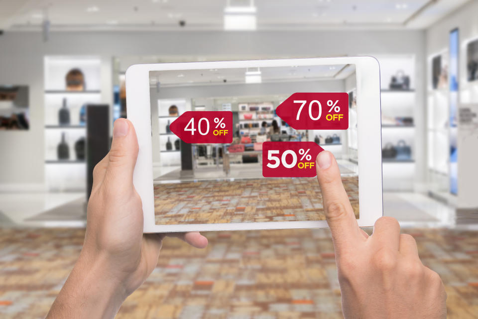 Augmented reality marketing concept. Hand holding digital tablet smart phone use AR application to check special sale price in retail fashion shop mall