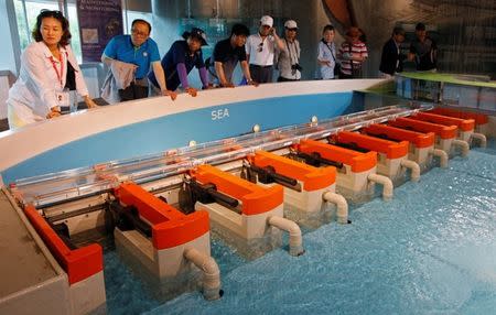 FILE PHOTO: Tourists watch a demonstration of how the Marina Barrage dam works at a gallery in the Marina Barrage facility in Singapore May 29, 2013. REUTERS/Edgar Su/File Photo