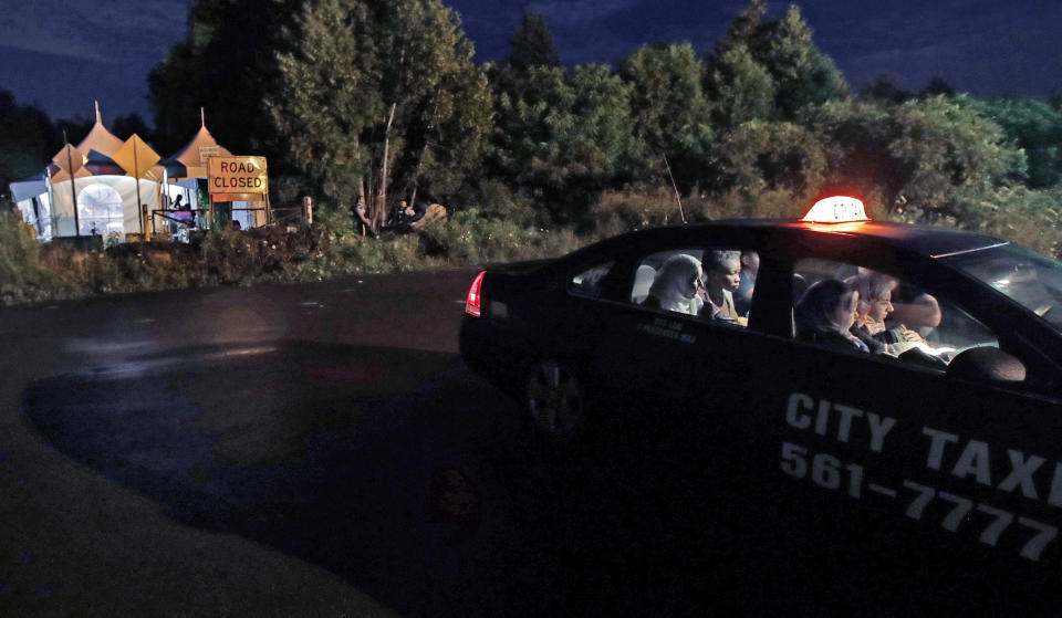 FILE - In this Aug. 8, 2017, file photo, a taxi filled with women from various nations pay their fare as they arrive at an unofficial border station across from Saint-Bernard-de-Lacolle, Quebec on Roxham Road in Champlain, N.Y. Since early 2017, when people who despaired of finding a permanent safe haven in the United States began turning to Canada for help, around 50,000 people have illegally entered Canada, many through Roxham Road in upstate New York. A case being heard in a Toronto court could end the use of Roxham Road. (AP Photo/Charles Krupa, File)