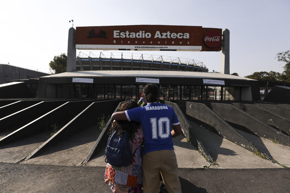 Una pareja, incluido un hombre con una camiseta que lleva el número 10 de Diego Maradona, se abraza frente al estadio Azteca de la Ciudad de México el miércoles 25 de noviembre de 2020 (AP Foto/Eduardo Verdugo)