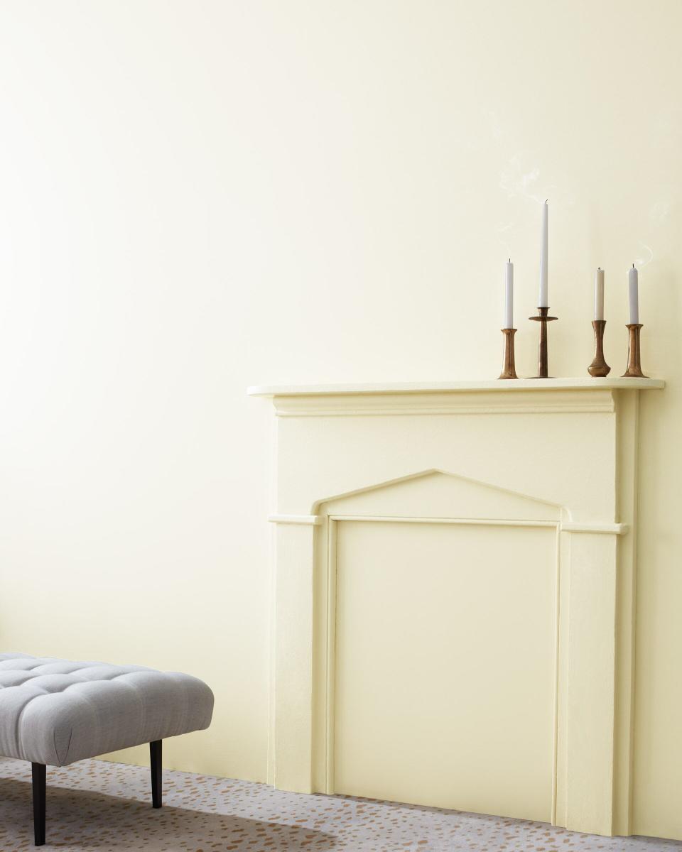 A wall, accented by a built-in mantle and varied candle sticks, painted in Cloud White by Benjamin Moore. 