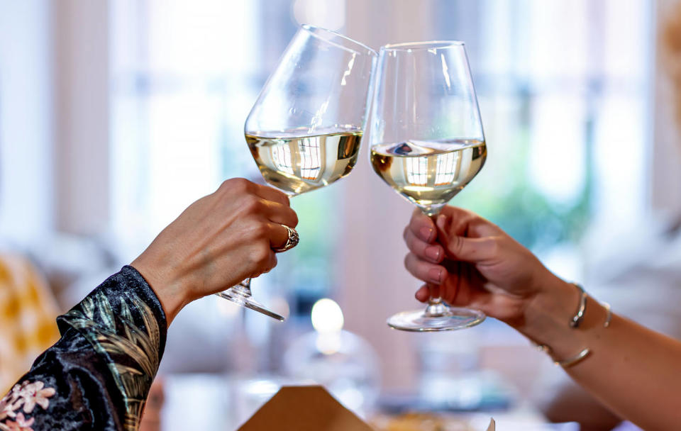 Women's hands holding glasses toasting. (Getty Images)