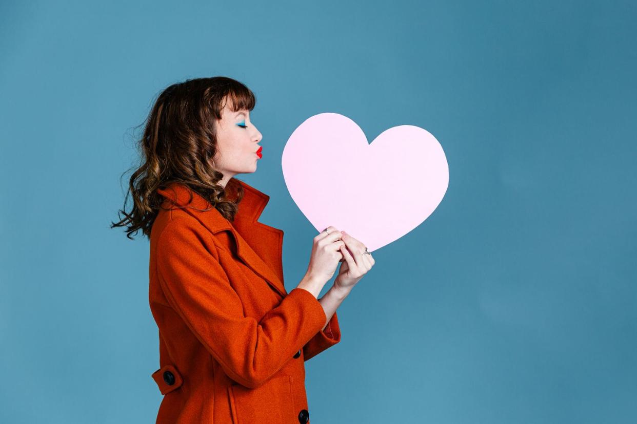 young woman holding paper pink heart