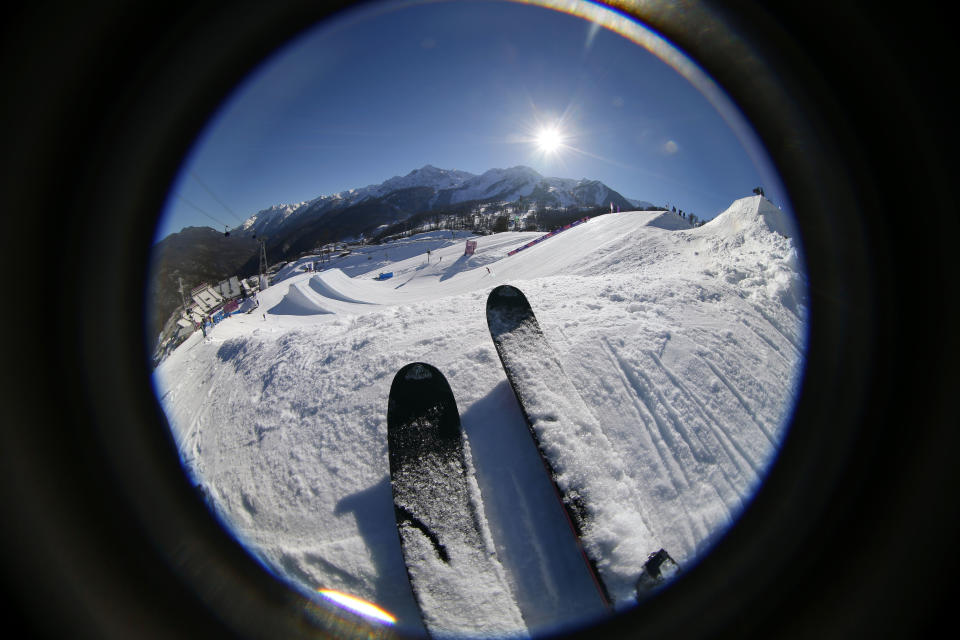 A volunteer watches a ski slopestyle training session at the Rosa Khutor Extreme Park, prior to the 2014 Winter Olympics, Wednesday, Feb. 5, 2014, in Krasnaya Polyana, Russia. (AP Photo/Sergei Grits)