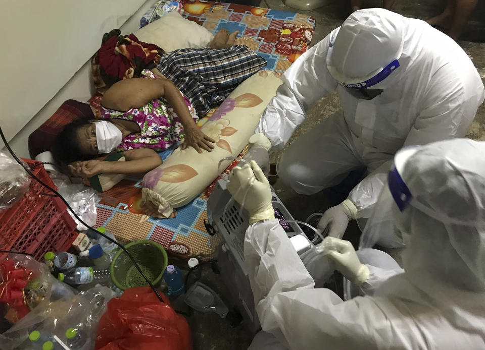 Volunteers from the "Saimai Will Survive" group in protective gear prepare oxygen for a struggling woman infected with COVID-19 on July 23, 2021, in Bangkok, Thailand. As Thailand's medical system struggles beneath a surge of coronavirus cases, ordinary people are helping to plug the gaps, risking their own health to bring care and supplies to often terrified, exhausted patients who've fallen through the cracks. (AP Photo/Tassanee Vejpongsa)