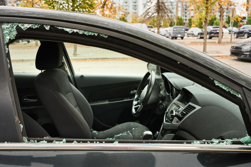 Shattered glass of a passenger window of a car on a city street the morning after a break in