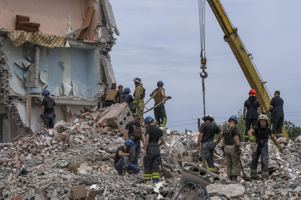 Rescue workers sift through rubble at the scene in the after math of a Russian rocket that hit an apartment residential block, in Chasiv Yar, Donetsk region, eastern Ukraine, Sunday, July 10, 2022. At least 15 people were killed and more than 20 people may still be trapped in the rubble, officials said Sunday. (AP Photo/Nariman El-Mofty)