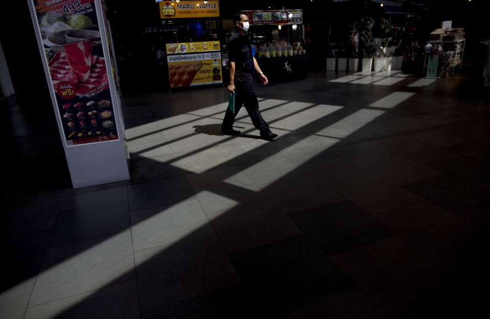 A security guard with a protective face mask walks at the entrance to a supermarket in Bangkok, Thailand, Tuesday, March 24, 2020. Most popular shopping malls remained shut in Bangkok, except supermarkets and pharmacies to combat the spread of new coronavirus. For most people, the new coronavirus causes only mild or moderate symptoms. For some, especially older adults it can cause more severe illness. (AP Photo/Gemunu Amarasinghe)