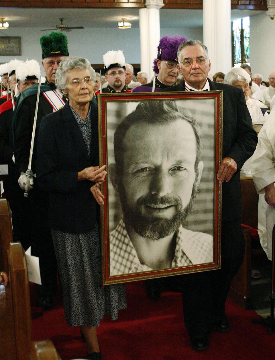 Sister Marita Rother, left, and Tom Rother, right, carry a framed photograph of their brother, Father Stanley Rother, at a mass in honor of his memory in 2006.