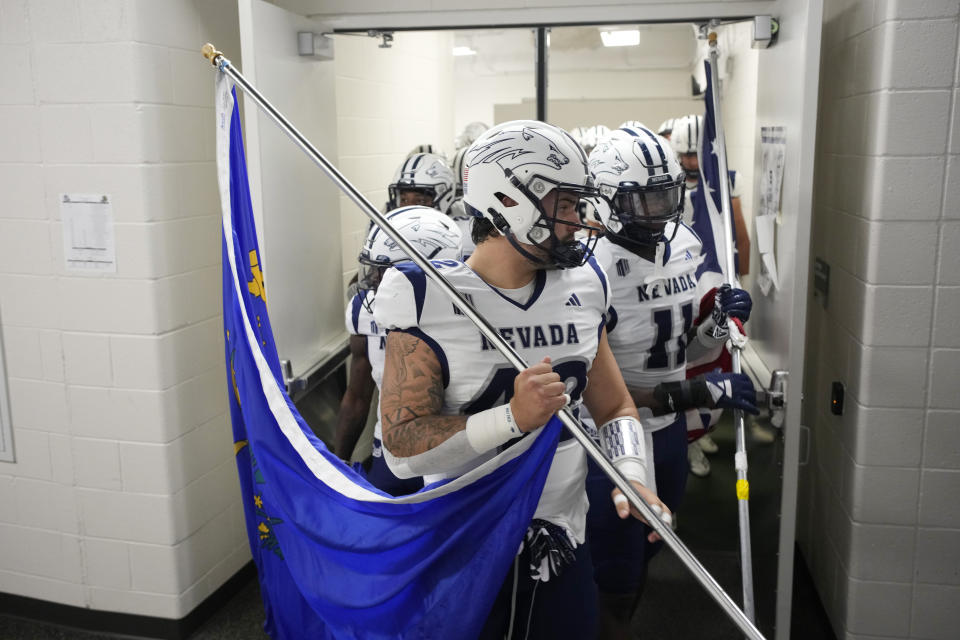 Nevada linebackers Jackson LaDuke, front, and Marcel Walker-Burgess carry flags as they lead the team out of the locker room and o to the field for an NCAA college football game against Colorado State, Saturday, Nov. 18, 2023, in Fort Collins, Colo. (AP Photo/David Zalubowski)