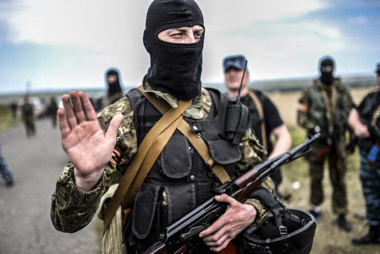 An armed pro-Russian separatist gestures as he blocks the way to the crash site of flight MH17, in east Ukraine on July 20, 2014