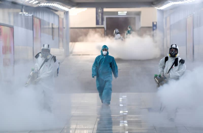 Volunteers in protective suits disinfect a railway station as the country is hit by an outbreak of the new coronavirus, in Changsha