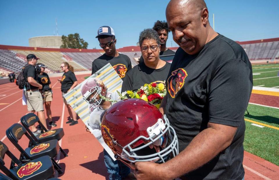 Justin McAllister’s father, Lloyd McAllister, holds Justin’s helmet signed by players and staff, as he stands with Justin’s mother, Mary, and brothers Jordan and Jack after they held a ceremony before their game at Sacramento City College on Saturday, Sept. 16, 2023. It was the team’s first game since Justin’s death on Sept. 11 during a practice.