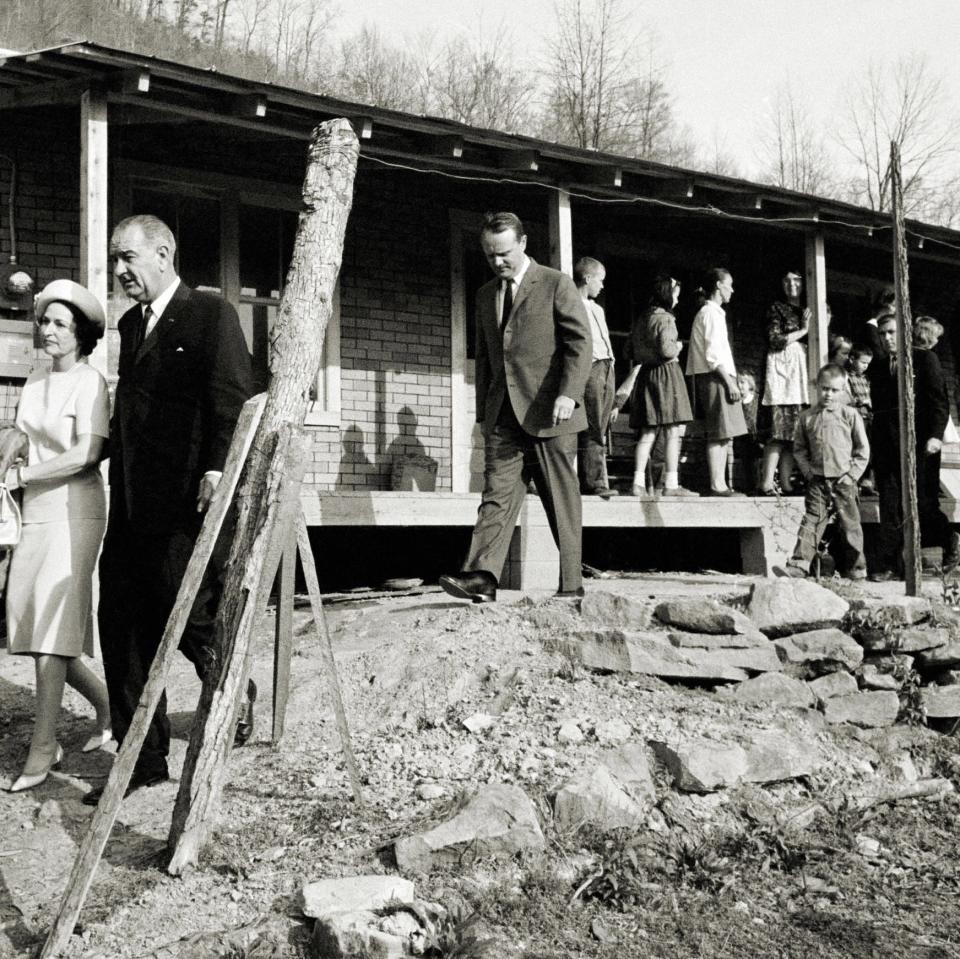 **FILE** President Lyndon Johnson and his wife, Lady Bird, center left, leave the home in Inez, Ky., of Tom Fletcher, a father of eight who told Johnson he'd been out of work for nearly two years, in this April 24, 1964, file photo.  The president visited the Appalachian area in Eastern Kentucky  to see conditions firsthand and announce his War on Poverty from the Fletcher porch.  (AP Photo/FILE)