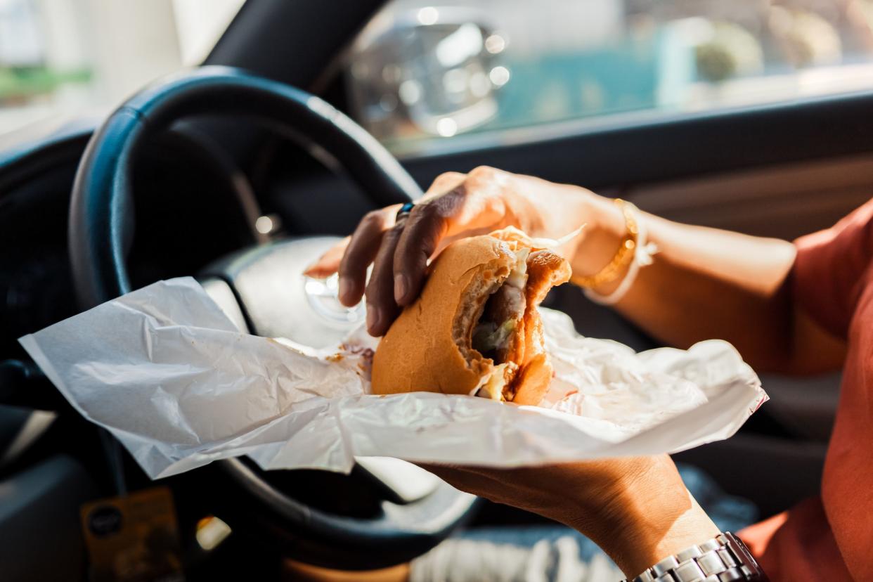 Man eating hamburger in car.