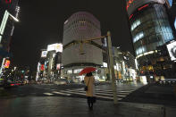 FILE - In this March 28, 2020, file, photo, a woman stands at empty Ginza shopping district in Tokyo Saturday, March 28, 2020. Before the Olympics were postponed, Japan looked like it had coronavirus infections contained, even as they spread in neighboring countries. Now that the games have been pushed to next year, Tokyo’s cases are spiking, and the city's governor is requesting that people stay home, even hinting at a possible lockdown. (AP Photo/Eugene Hoshiko, File)