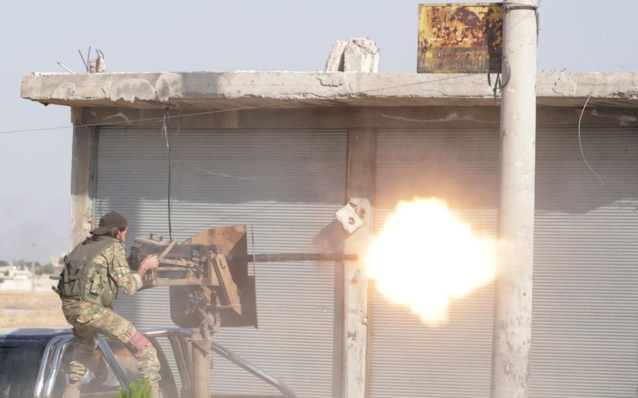 A Turkey-backed Syrian rebel fighter fires a weapon in the town of Tal Abyad - REUTERS