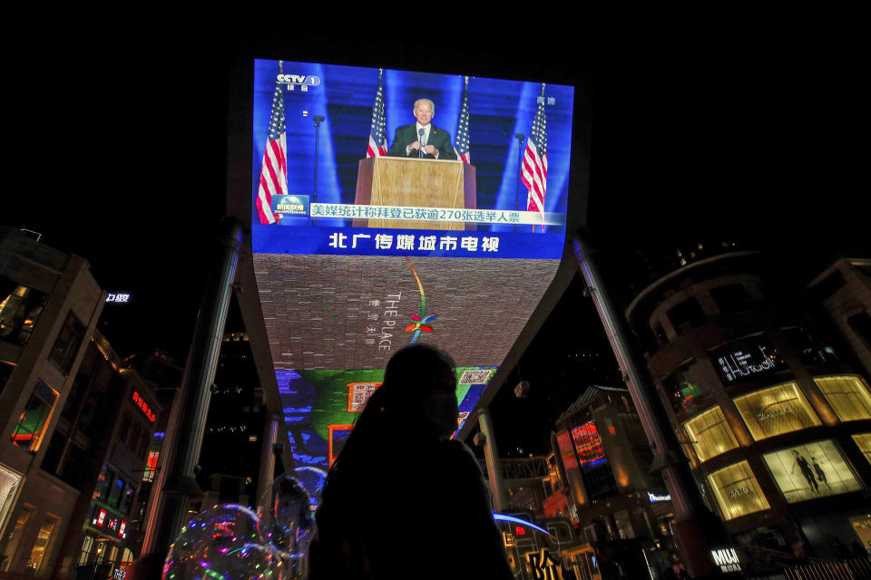 A woman sells balloons near a giant TV screen broadcasting a news of U.S. President-elect Joe Biden delivers his speech, at a shopping mall in Beijing, Sunday, Nov. 8, 2020. World leaders on Sunday cheered Joe Biden's election as U.S. president as a chance to enhance cooperation on climate change, the coronavirus and other problems after four years of President Donald Trump's rejection of international alliances. (AP Photo/Andy Wong)