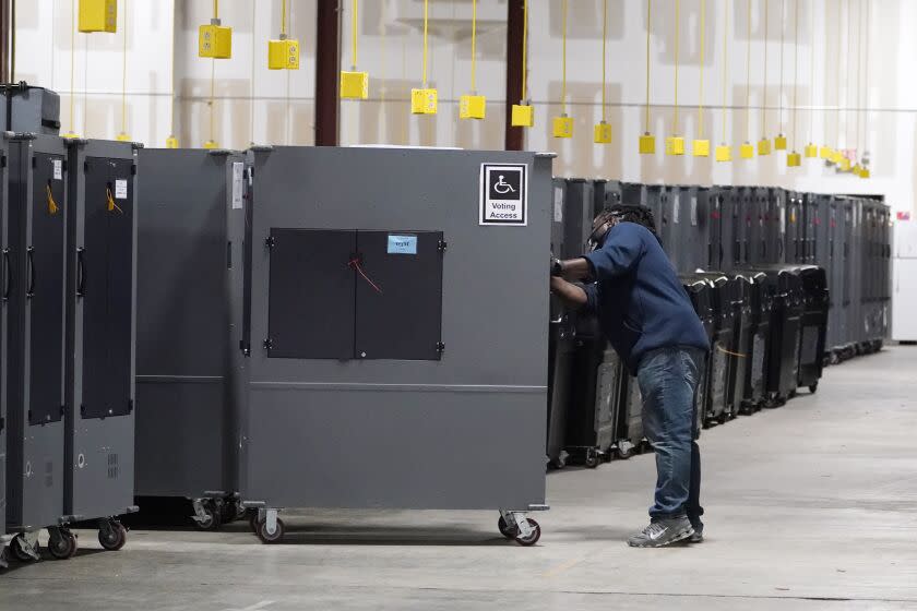 FILE - A worker returns voting machines to storage at the Fulton County Election preparation center, Nov. 4, 2020 in Atlanta, Ga. Testing before and after elections show the voting machines accurately tally the ballots, contradicting a relentless campaign of unfounded conspiracy theories that has undermined confidence in voting equipment throughout the U.S. (AP Photo/John Bazemore, File)