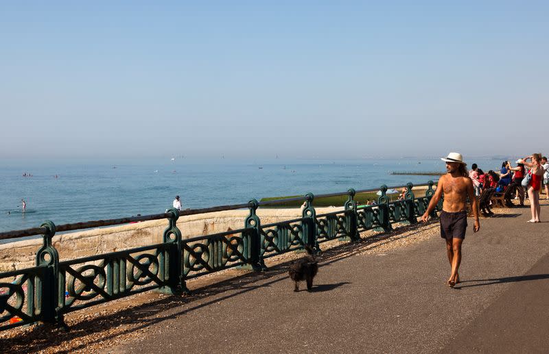 Ben Palmer walks with his dog Otto at the sea front during hot weather in Brighton