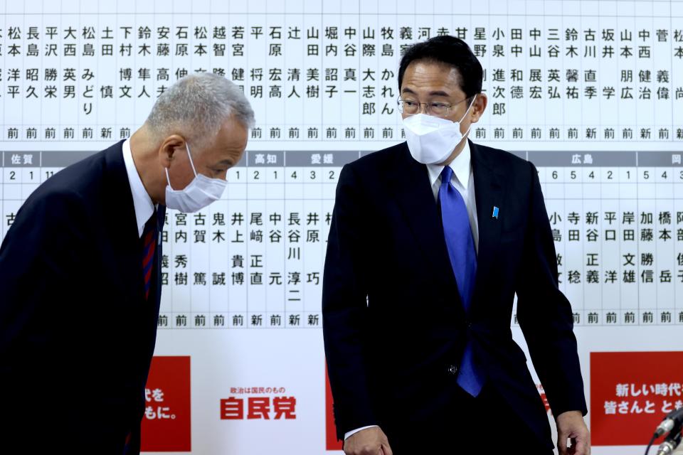 Japan's ruling Liberal Democratic Party General Secretary Akira Amari, left, bows to Prime Minister and party leader Fumio Kishida at the party headquarters in Tokyo, Sunday, Oct. 31, 2021. Japanese Prime Minister Fumio Kishida’s governing coalition is expected to keep a majority in a parliamentary election Sunday but will lose some seats in a setback for his weeks-old government grappling with a coronavirus-battered economy and regional security challenges, according to exit polls. (Behrouz Mehri, Pool via AP)