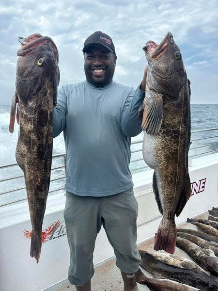 Ish Monroe, professional bass angler, hefts up two giant lingcod that he hooked while fishing at Rittenburg Bank aboard the California Dawn 2 on August 20.