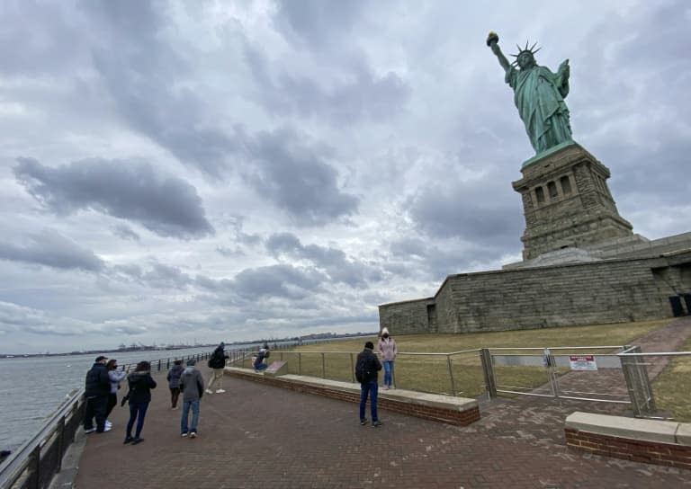 Des visiteurs au pied de la statue de la Liberté, le 1er mars 2021 à New York - Kena Betancur © 2019 AFP