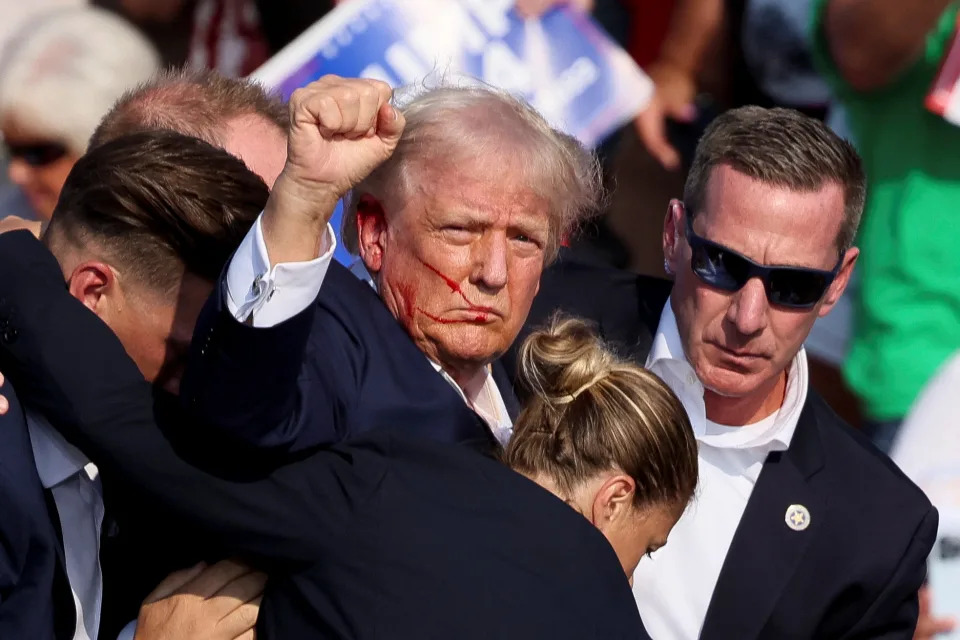 Republican presidential candidate and former U.S. President Donald Trump gestures as he is assisted by U.S. Secret Service after gunfire rang out during a campaign rally at the Butler Farm Show in Butler, Pennsylvania, U.S., July 13, 2024. REUTERS/Brendan McDermid