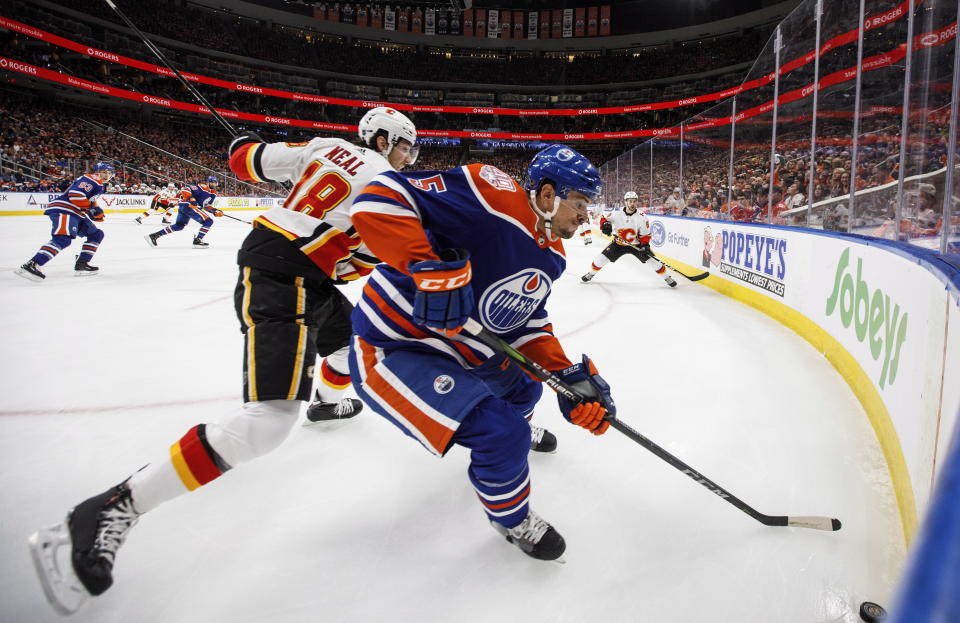 Calgary Flames' James Neal (18) and Edmonton Oilers' Kevin Gravel (5) battle for the puck during first period NHL hockey action in Edmonton, Alberta on Sunday, Dec. 9, 2018. (Jason Franson/The Canadian Press via AP)