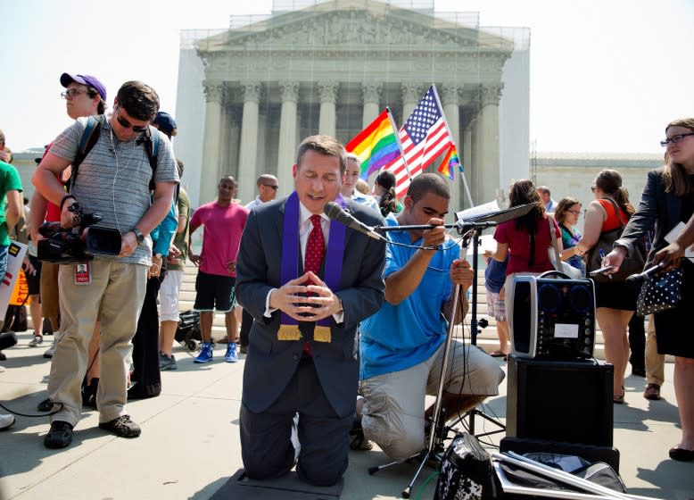 The Rev. Rob Schenck, an opponent of gay marriage, center, prays after the U.S. Supreme Court gave a landmark victory to the gay-rights movement, striking down a federal law that denies benefits to same-sex married couples and clearing the way for weddings to resume in California.